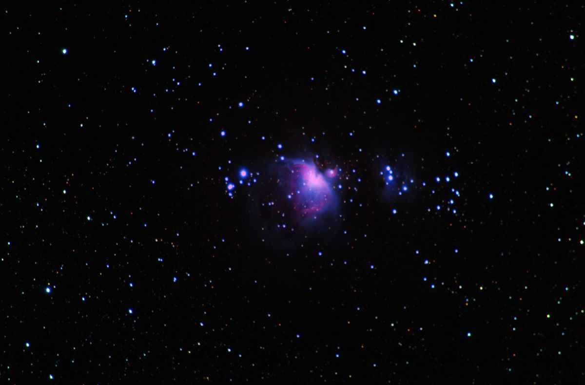 The Orion Nebula (M42) glowing pink around the Trapezium, with the blue Running Man Nebula (NGC 1977) to the upper right