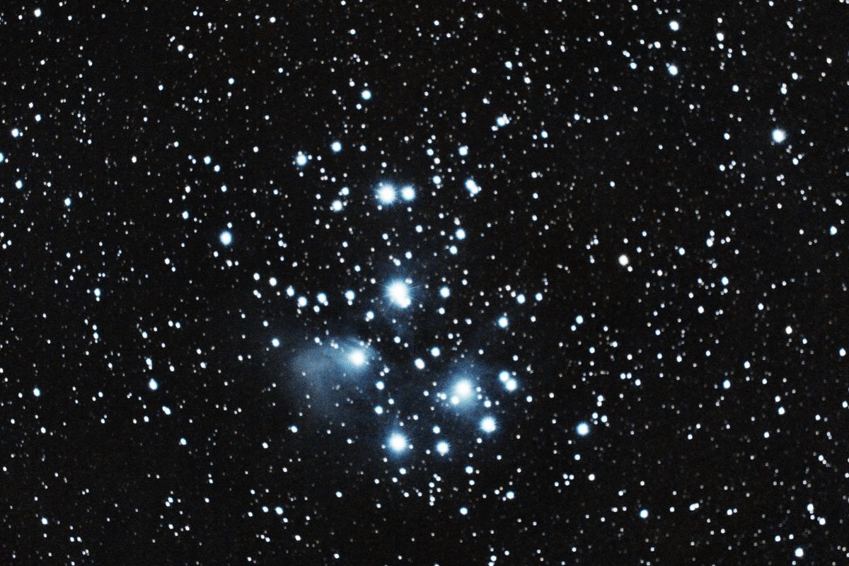 The Pleiades open cluster (M45), bright blue stars wrapped in faint blue reflection nebulosity
