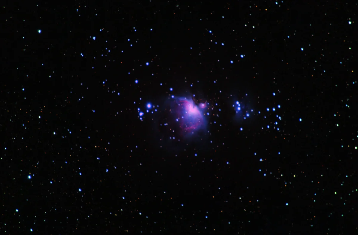 The Orion Nebula (M42) glowing pink around the Trapezium, with the blue Running Man Nebula (NGC 1977) to the upper right